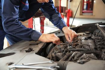 Male mechanic repairing car in service center�
