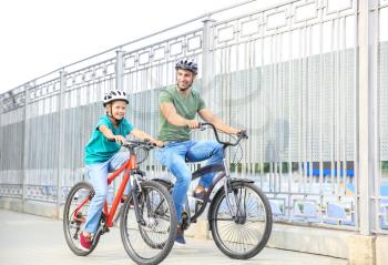 Happy father and son riding bicycles outdoors�