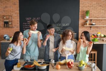 Happy friends eating fruits together in kitchen�