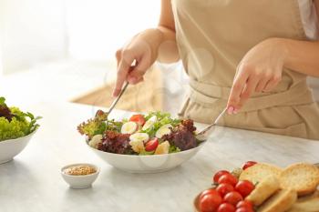 Woman preparing tasty salad in kitchen�