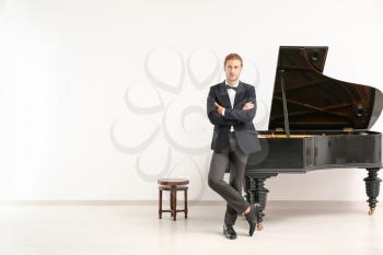 Man near grand piano against white wall�