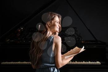 Young woman with note sheets at grand piano�