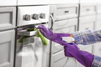 Woman cleaning oven in kitchen�