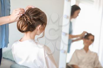 Professional hairdresser working with young bride at home�