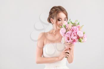 Portrait of beautiful young bride with wedding bouquet on light background�