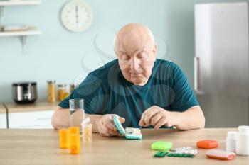 Elderly man with different pills at home�