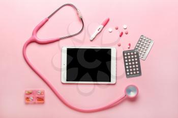Modern tablet computer with stethoscope and pills on color background�