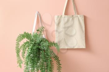Eco bags with plant on color background�