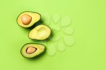 Halves of ripe avocado on color background�