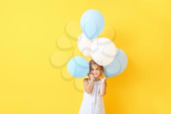 Little girl with balloons on color background�