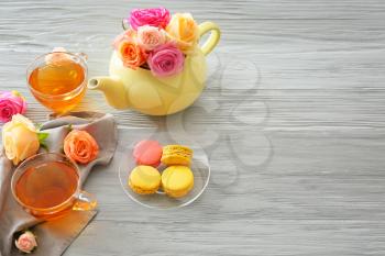 Beautiful rose flowers with tea and dessert on grey table�