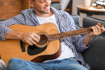 Handsome man playing guitar at home�