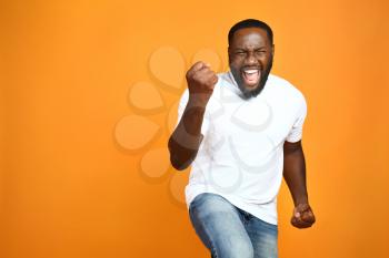 Happy African-American man on color background�