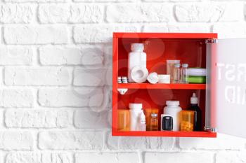 First aid kit hanging on white brick wall�