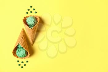 Waffle cones with tasty spirulina ice-cream on color background�
