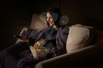 Young woman with popcorn watching movie at home late in evening�