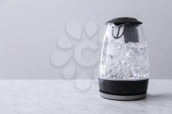 Transparent electric kettle with boiling water on table�