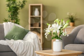Beautiful lily flowers in vase on table in room�