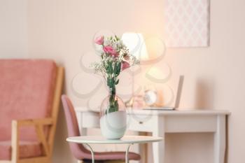 Beautiful flowers in vase on table in room�
