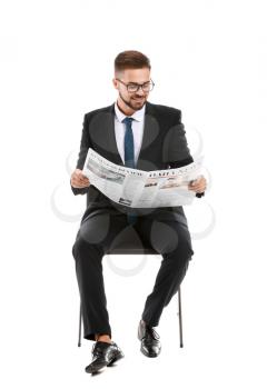 Handsome businessman with newspaper sitting on chair against white background�