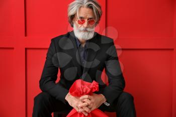 Portrait of stylish Santa Claus with bag on color background�