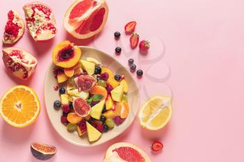 Plate with tasty fruit salad on color background�