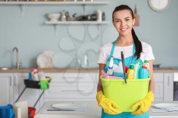 Female janitor with cleaning supplies in kitchen�