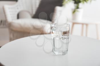 Glass of fresh water on table in room�