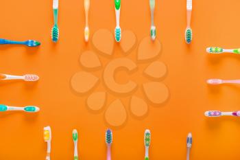 Frame made of tooth brushes on color background�