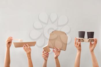 Many hands with containers for food delivery on grey background�