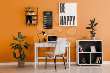 Stylish workplace with laptop near color wall�