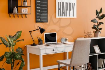 Stylish workplace with laptop near color wall�