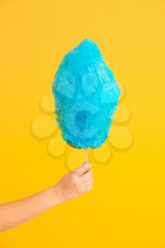 Female hand with tasty cotton candy on color background�