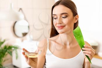 Beautiful young woman with aloe vera in bathroom�