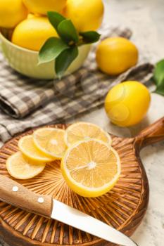 Cutting board with ripe lemon and knife on light background�