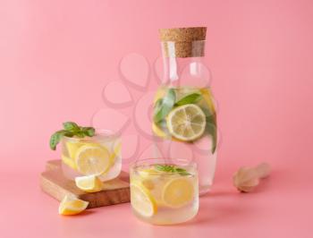 Bottle and glasses of fresh lemonade on color background�