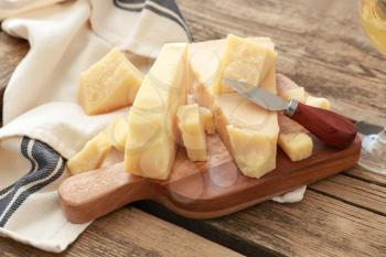 Board with tasty Parmesan cheese on wooden table�