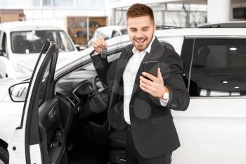 Happy male buyer near new car in salon�