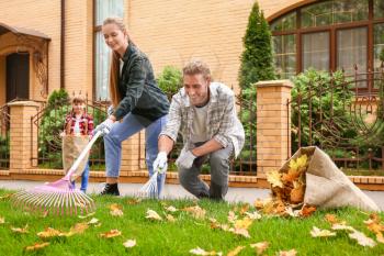 Family cleaning up autumn leaves outdoors�