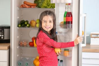 Little Asian girl choosing food from fridge in kitchen�