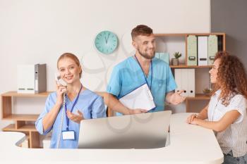 Male and female receptionists working at desk in clinic�