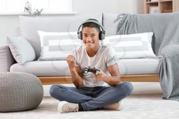 Happy African-American teenager boy playing video games at home�