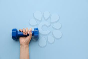 Female hand with dumbbell on color background�
