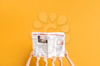 Female hands with newspapers on color background�