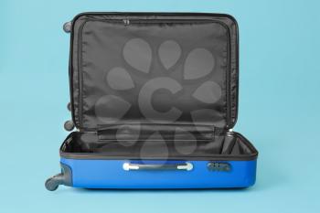 Open empty suitcase on color background�