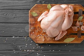 Raw chicken with spices on wooden background�