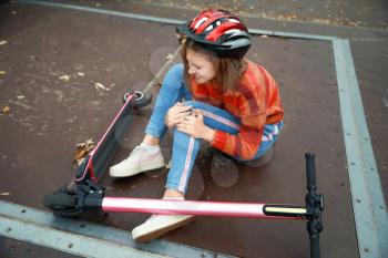 Teenage girl fallen off her kick scooter outdoors�