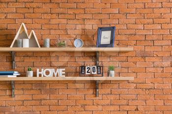 Shelves with decor hanging on brick wall�