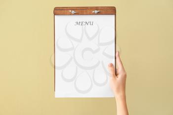 Female hand with blank menu on color background�