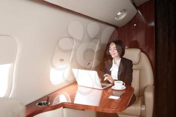 Businesswoman with laptop on board the modern private airplane�
